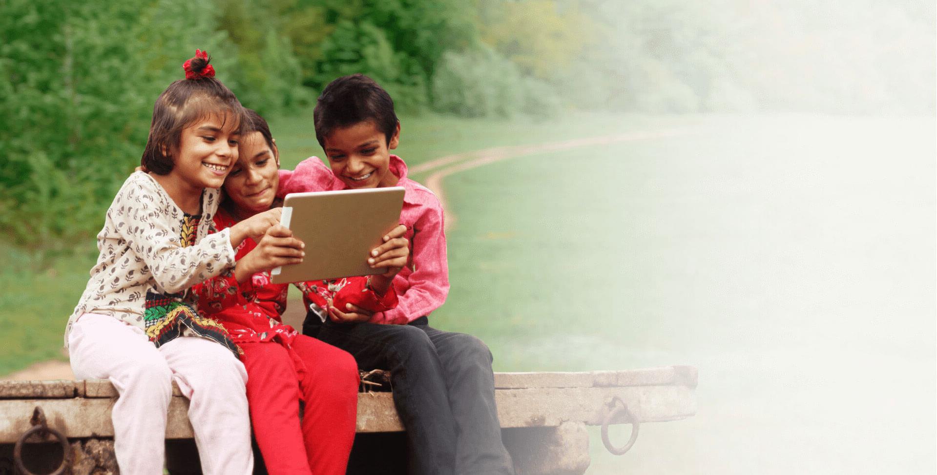 Niños sonrientes en el campo usando una tablet 